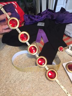 a woman's necklace with red stones and gold circles around it on a table