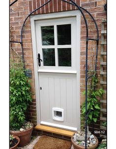 a white door with a dog's kennel in the middle and plants around it