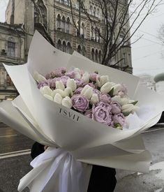 a woman holding a bouquet of flowers on the street in front of an old building