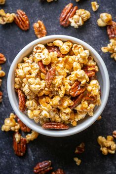 a white bowl filled with nuts on top of a black table next to pecans