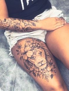 a woman with a lion tattoo on her thigh, sitting in front of a bed