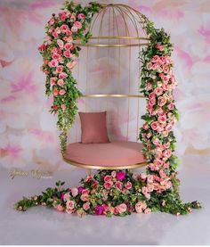 a birdcage with pink flowers and greenery on the sides is shown in front of a floral backdrop