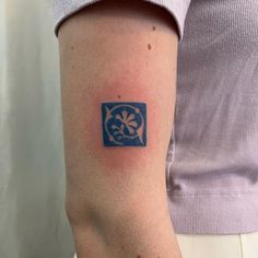 a woman's arm with a blue and white flower tattoo on the left upper arm