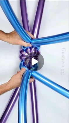 two hands are holding onto an inflatable purple and blue object that looks like a star