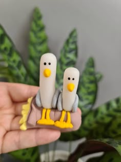 two plastic birds sitting on top of each other in front of some green plant leaves