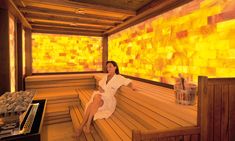 a woman sitting in a sauna with yellow tiles on the wall