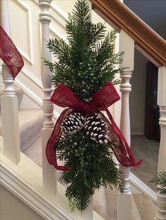 a christmas tree with pine cones and red ribbon on the banister