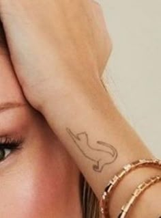 a close up of a person with a tattoo on their arm and hand behind her head