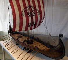 a model ship with red and white stripes on it's sails, sitting on a table