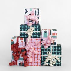 a stack of wrapped presents sitting on top of each other with bows and ribbons around them