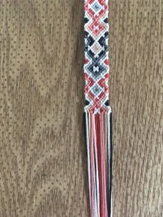 a red, white and black bracelet with tassels hanging from it's side