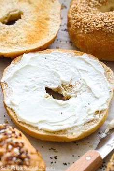 bagels with white frosting and sprinkles sit on a table next to a knife