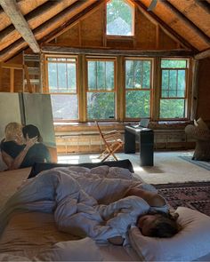 a woman laying on top of a bed in a bedroom next to a painting and window