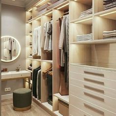 a walk in closet filled with lots of white drawers and shelves next to a mirror