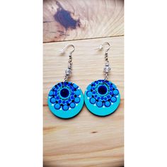 a pair of earrings with blue circles and beads on wooden table next to wood planks