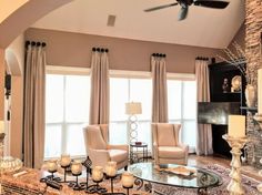 a living room filled with furniture and a fire place next to a window covered in curtains