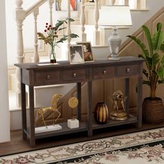 a wooden table sitting under a stair case next to a potted plant on top of a hard wood floor