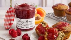 muffins with raspberry sauce and fresh fruit next to them on a table