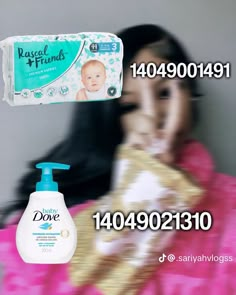 a woman holding a baby in her arms next to a box of diapers and a hand sanitizer