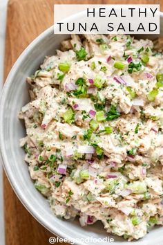 a white bowl filled with tuna salad on top of a wooden cutting board