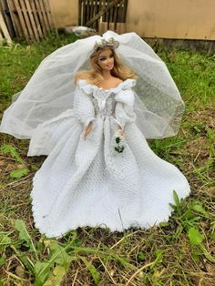 a barbie doll wearing a white wedding dress and veil in the grass with her hands on her hips