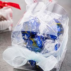 a clear box filled with blue and white chocolate candies next to a red bow