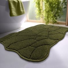 a green rug is on the floor in front of a white bathtub and window