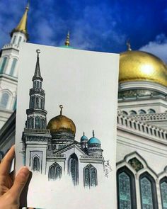 a hand holding up a drawing of a building with two domes on it's sides