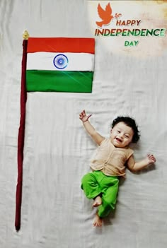 a baby laying on top of a bed next to a flag