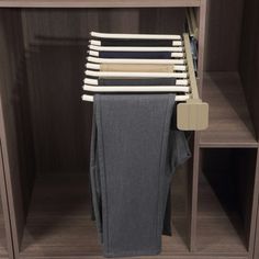 an open closet with clothes hanging on the rack and folded jeans in front of it