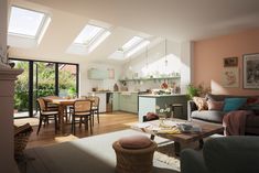 a living room filled with furniture next to a kitchen and dining room table under a skylight