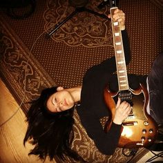 a woman laying on the floor with an electric guitar