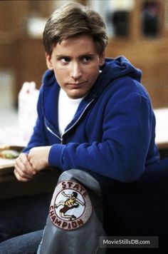 a young man sitting at a table with his hand on his knee