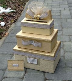 three gold boxes stacked on top of each other with ribbons and bows around the edges