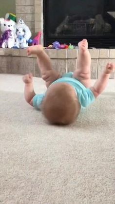 a baby laying on the floor in front of a fire place