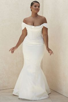 a woman in a white wedding dress posing for the camera with her hands out and one hand on her hip