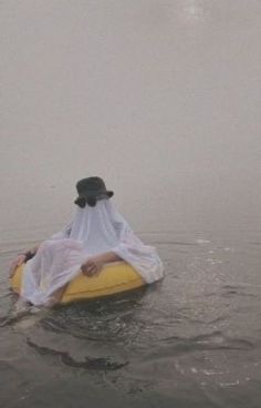 a person floating on top of a yellow raft in the middle of foggy water