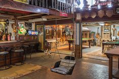 a room filled with lots of wooden furniture and hanging chairs next to a pool table