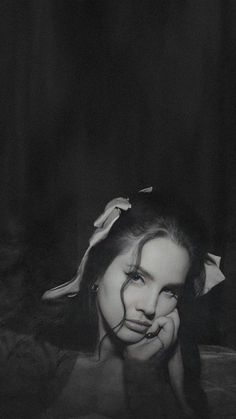 black and white photograph of a woman with her head tilted to the side, in front of a dark background