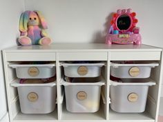 a white shelf with several bins and a stuffed animal