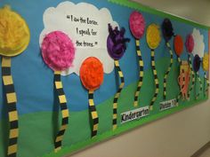 a bulletin board with colorful paper flowers and words written on the front, along with an image of trees