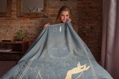 a woman is holding up a blanket with an image of the sun and stars on it