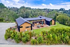 an aerial view of a house in the middle of trees and grass with mountains in the background