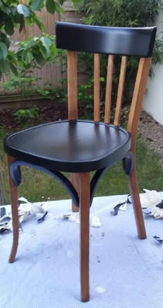 a wooden chair sitting on top of a table next to a bird in the yard