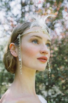 a woman wearing a head piece with feathers on it's head and pearls in her hair