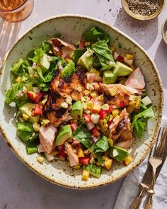 a salad with chicken, corn and avocado in a bowl on a table