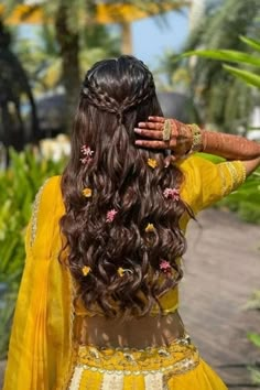 a woman with long hair wearing a yellow dress and holding her hands on her head