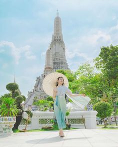 a woman holding an umbrella and standing in front of a building with a pagoda on it