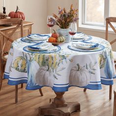 a dining room table set for two with pumpkins and gourds on it