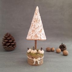 a small white christmas tree sitting on top of a wooden box next to pine cones